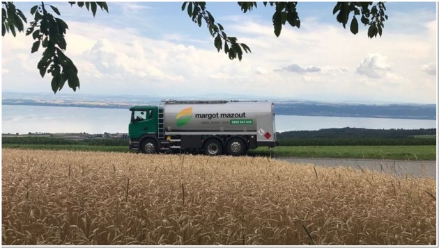 Camion Margot Mazout traversant un champ avec vue sur un lac