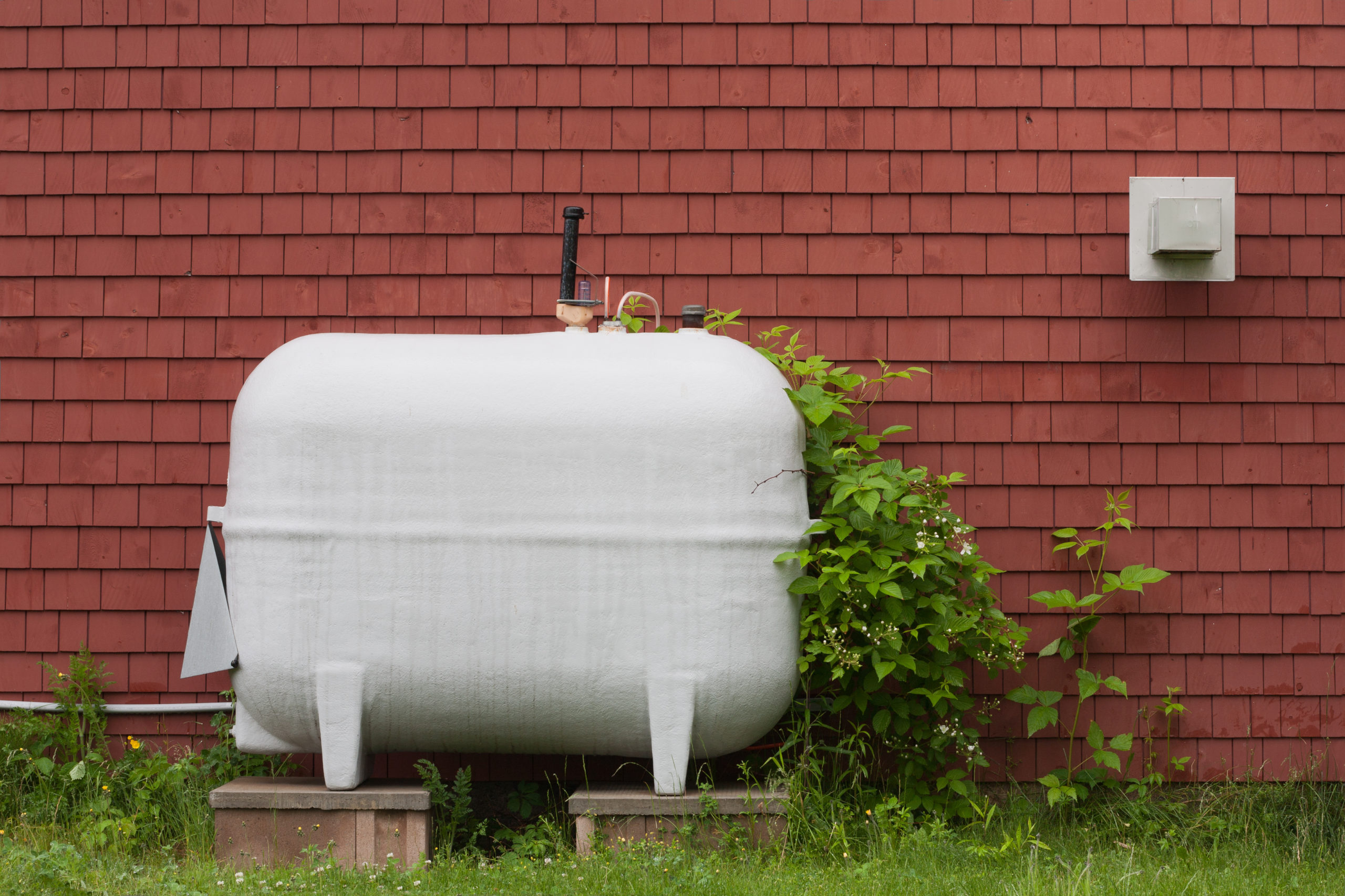 Heating fuel oil tank beside exterior wall.
